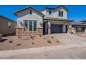 Charming two-story home with a gray stucco exterior, brick accents, and a paved driveway at 21430 W Meadowbrook Ave, Buckeye, AZ 85396