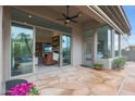 Covered patio featuring ceiling fan, desert landscaping, and multiple sliding glass doors at 3120 E Squaw Peak Cir, Phoenix, AZ 85016