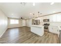 Open-concept layout with modern gray vinyl flooring, a ceiling fan, and a bright kitchen with an island at 4207 W Poinsettia Dr, Phoenix, AZ 85029