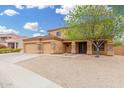 Tan two-story home with a three-car garage and low maintenance rock landscaping at 4419 W Lodge Dr, Laveen, AZ 85339