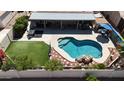 Aerial view of backyard oasis with pool, rock waterfall feature, patio, and artificial grass at 10318 W Luke Ave, Glendale, AZ 85307