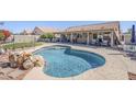 Relax in this sparkling blue pool featuring rock accents and an expansive patio area at 10318 W Luke Ave, Glendale, AZ 85307