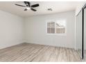 Bright bedroom with wood-look floors, a ceiling fan, and a large window at 12134 W Flores Dr, El Mirage, AZ 85335