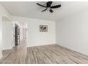 Bright, open living room with wood-look flooring and white walls and ceiling fan at 12134 W Flores Dr, El Mirage, AZ 85335