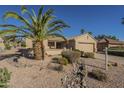 Single-story home featuring desert landscaping, a palm tree, and a two-car garage at 19746 N Wind Rose Way, Surprise, AZ 85374