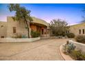 Attractive desert home featuring a circular driveway, mature landscaping, and covered entryway, offering inviting curb appeal at 10325 E Celestial Dr, Scottsdale, AZ 85262