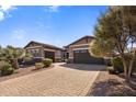 A home with a paver driveway, beautiful landscaping, and a three car garage at 1163 E Holbrook St, Gilbert, AZ 85298