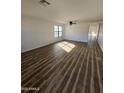 Bright and spacious living room featuring wood-look floors, a ceiling fan, and large windows at 15581 W Caribbean Ln, Surprise, AZ 85379