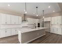 Bright kitchen with white cabinets, stainless hood, and large island with quartz countertops at 23805 N 163Rd Dr, Surprise, AZ 85387