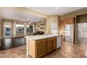 An open-concept kitchen boasts wood cabinets, an island with sink, tile floors, and an open view of the living area at 612 E Riviera Dr, Chandler, AZ 85249