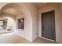 Inviting porch with arched entryway featuring a window and a dark wood door at 16011 W Clinton St, Surprise, AZ 85379