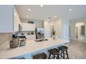 Bright kitchen featuring white cabinets, stainless steel appliances, and a breakfast bar with wooden barstools at 24886 N 167Th Dr, Surprise, AZ 85387