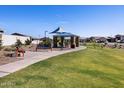 Community playground featuring a shaded structure with picnic tables, a bench, and lush green space at 35533 N Seedling St, San Tan Valley, AZ 85144