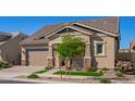 Inviting home showcasing a two-car garage, stone detailing, complemented by a lush green lawn and blooming flowers at 4156 E Bernice St, Gilbert, AZ 85295