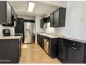 Kitchen with wood-look floors, stainless steel appliances, dark cabinets and light countertops at 11613 N 21St Ave, Phoenix, AZ 85029