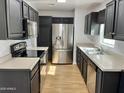 Well-lit kitchen featuring stainless steel appliances, dark cabinetry, and light countertops at 11613 N 21St Ave, Phoenix, AZ 85029