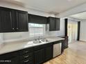 Kitchen sink and stainless steel dishwasher, plus view into adjacent room with sliding glass door at 11613 N 21St Ave, Phoenix, AZ 85029