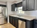 Kitchen with stainless steel appliances, dark cabinetry, a window above sink, and light countertops at 11613 N 21St Ave, Phoenix, AZ 85029
