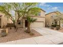 Two story tan home featuring desert landscaping, a two-car garage, and a lovely mature tree at 19072 N Ventana Ln, Maricopa, AZ 85138