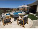 Cozy backyard featuring a pool, comfortable seating area with umbrella, and lush faux grass at 26904 W Kerry Ln, Buckeye, AZ 85396