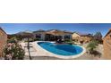 Panoramic view of the backyard pool with stone surround, lush landscaping, and covered patio, ideal for outdoor living at 26904 W Kerry Ln, Buckeye, AZ 85396