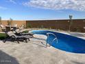 Backyard with lounge chairs, a seating area and a freeform blue swimming pool against a red brick fence at 26904 W Kerry Ln, Buckeye, AZ 85396