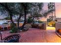 Enchanting brick patio with lush greenery, mature trees, and an inviting fire pit create a serene outdoor space at 3258 E Vogel Ave, Phoenix, AZ 85028