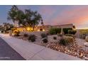 The home showcases desert landscaping and mature trees, complemented by a well-maintained stucco facade at sunset at 3258 E Vogel Ave, Phoenix, AZ 85028