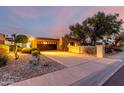 Front exterior showcases desert landscaping, mature trees, and a paved driveway leading to the home at sunset at 3258 E Vogel Ave, Phoenix, AZ 85028