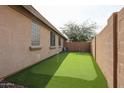 Backyard featuring artificial turf, ideal for recreation and relaxing, with a privacy wall and mature tree at 6796 W Evergreen Ter, Peoria, AZ 85383