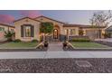 Charming single-story home with a beautifully landscaped front yard, decorative wrought iron gate, and a welcoming walkway at 7589 W Firebird Dr, Glendale, AZ 85308