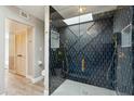 Modern bathroom showcasing a glass shower with stylish black tiling and gold fixtures, plus skylight at 7905 E Plaza Ave, Scottsdale, AZ 85250