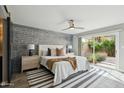 Main bedroom with brick accent wall, sliding glass doors to the backyard, ceiling fan, and neutral decor at 7905 E Plaza Ave, Scottsdale, AZ 85250