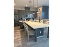 Kitchen with eat-in island, modern lighting, stainless steel appliances, quartz counters, and gray cabinetry at 14870 W Encanto Blvd # 2084, Goodyear, AZ 85395