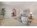 Bright living room with carpeted floors, a seating area, and an arched entryway adds architectural interest at 15602 N 56Th Pl, Scottsdale, AZ 85254