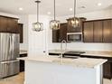 Modern kitchen featuring dark wood cabinets, stainless steel appliances, and a large island with pendant lighting at 8613 W Warner St, Tolleson, AZ 85353