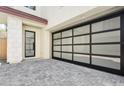 Two-car garage with modern glass panel door and stone-accented entryway with black framed door at 1 Easy St # 11, Carefree, AZ 85377