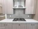 Close up on the gray cabinets, stainless steel range hood, gray tile backsplash, and gas cooktop at 1 Easy St # 6, Carefree, AZ 85377