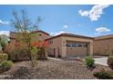 Side view of a tan home with a two-car garage, desert landscaping and a secure gated entrance at 12915 W Lone Tree Trl, Peoria, AZ 85383