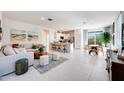 Bright and airy living room featuring tile flooring, a modern sofa, and seamless access to the kitchen and dining area at 15033 W Hackamore Dr, Surprise, AZ 85387