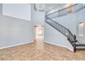 Open-concept living area featuring tile flooring, neutral paint, and a staircase with decorative black metal banister at 15033 W Statler St, Surprise, AZ 85374