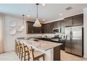 Beautiful kitchen featuring granite countertops, stainless steel appliances, dark wood cabinets, and a breakfast bar at 15815 W Kendall St, Goodyear, AZ 85338