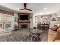 Cozy living room featuring a stone fireplace, ceiling fan, and access to the outdoor space at 9735 N 94Th Pl # 110, Scottsdale, AZ 85258