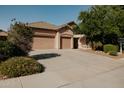 Charming single-story home features a spacious three-car garage and a shade tree in front yard at 13542 W Port Au Prince Ln, Surprise, AZ 85379