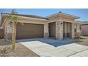 Charming single-level home features a spacious driveway, neutral-colored stucco, and stone-accented entryway pillars at 15005 W Gray Fox Trl, Surprise, AZ 85387