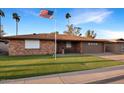 Traditional-style brick house with a lush green lawn, palm trees, and a flagpole displaying the American flag at 4729 E Dolphin Ave, Mesa, AZ 85206