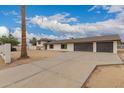 Spacious driveway leading to a three-car garage, surrounded by desert landscaping at 5038 W Acoma Dr, Glendale, AZ 85306