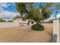 Side view of the property showcasing mature trees and neutral color scheme at 5038 W Acoma Dr, Glendale, AZ 85306