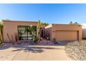 Desert home boasts tan stucco, lush xeriscaping, arched front door, and attached two car garage at 5970 N Echo Canyon Dr, Phoenix, AZ 85018