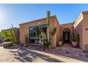 This desert home features tan stucco, lush xeriscaping, and an arched front door with attached garage at 5970 N Echo Canyon Dr, Phoenix, AZ 85018